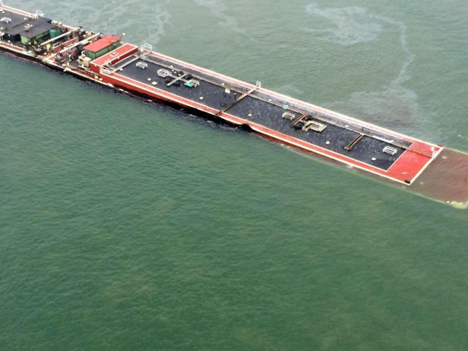 In this image provided by the U.S. Coast Guard a barge loaded with marine fuel oil sits partially submerged in the Houston Ship Channel, Saturday March 22, 2014. The bulk carrier Summer Wind, reported a collision between the Summer Wind and a barge, containing 924,000 gallons of fuel oil, towed by the motor vessel Miss Susan. The barge collided with a ship in Galveston Bay on Saturday, leaking an unknown amount of the fuel into the popular bird habitat as the peak of the migratory shorebird season was approaching. (AP Photo/U.S. Coast Guard, PO3 Manda Emery)