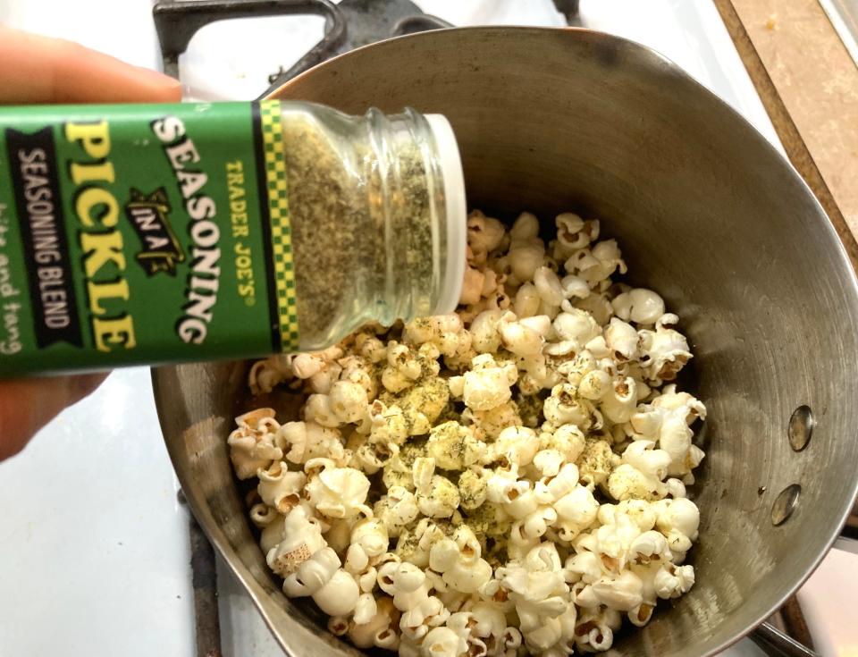 Adding pickle seasoning to a pot of popcorn.