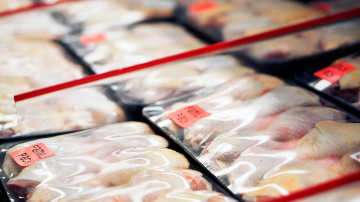  sealed packages of raw chicken arranged in a refrigerator at a grocery store 