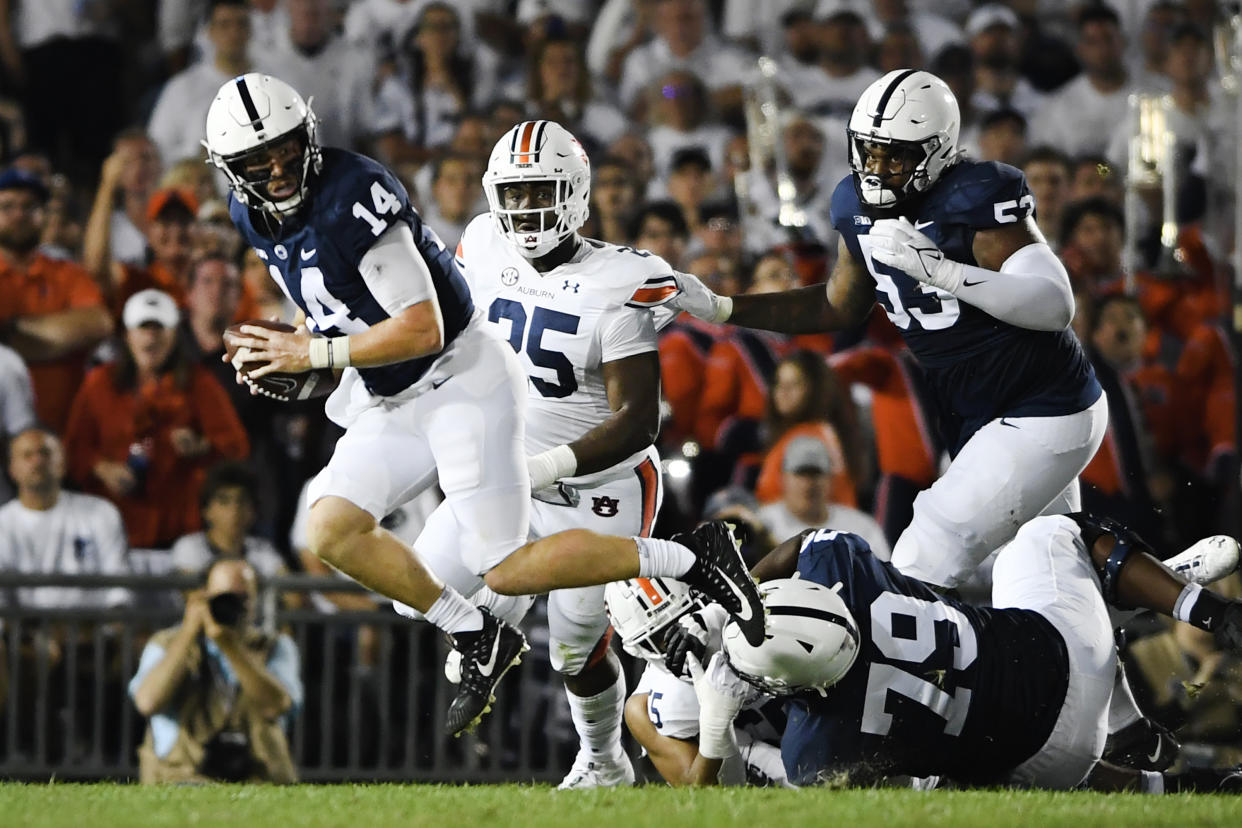 Penn State quarterback Sean Clifford (14) scrambles away from Auburn defensive end Colby Wooden (25) during an NCAA college football game against Auburn in State College, Pa., on Saturday, Sept. 18, 2021. (AP Photo/Barry Reeger)