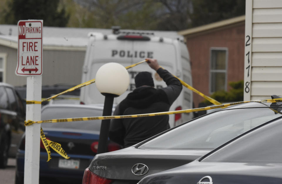 A Colorado Springs Police Department officer lifts up crime tape at the scene where multiple people were shot and killed early Sunday, May 9, 2021, in Colorado Springs, Colo. The suspected shooter was the boyfriend of a female victim at the party attended by friends, family and children. He walked inside and opened fire before shooting himself, police said. Children at the attack weren’t hurt and were placed with relatives. (Jerilee Bennett/The Gazette via AP)
