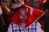 A supporter of newly elected Turkish Cypriot leader Ersin Tatar, with a Turkey flag on his head, celebrate after winning the Turkish Cypriots election, in the Turkish occupied area in the north part of the divided capital Nicosia, Cyprus, Sunday, Oct. 18, 2020. Ersin Tatar, a hardliner who favors even closer ties with Turkey and a tougher stance with rival Greek Cypriots in peace talks has defeated the leftist incumbent in the Turkish Cypriot leadership runoff. (AP Photo/Nedim Enginsoy)
