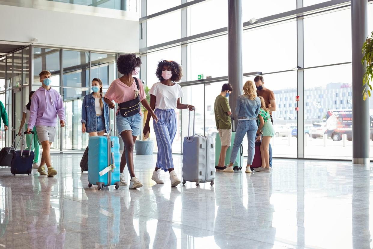 Passengers at the airport during the summertime with luggage, wearing N95 face masks