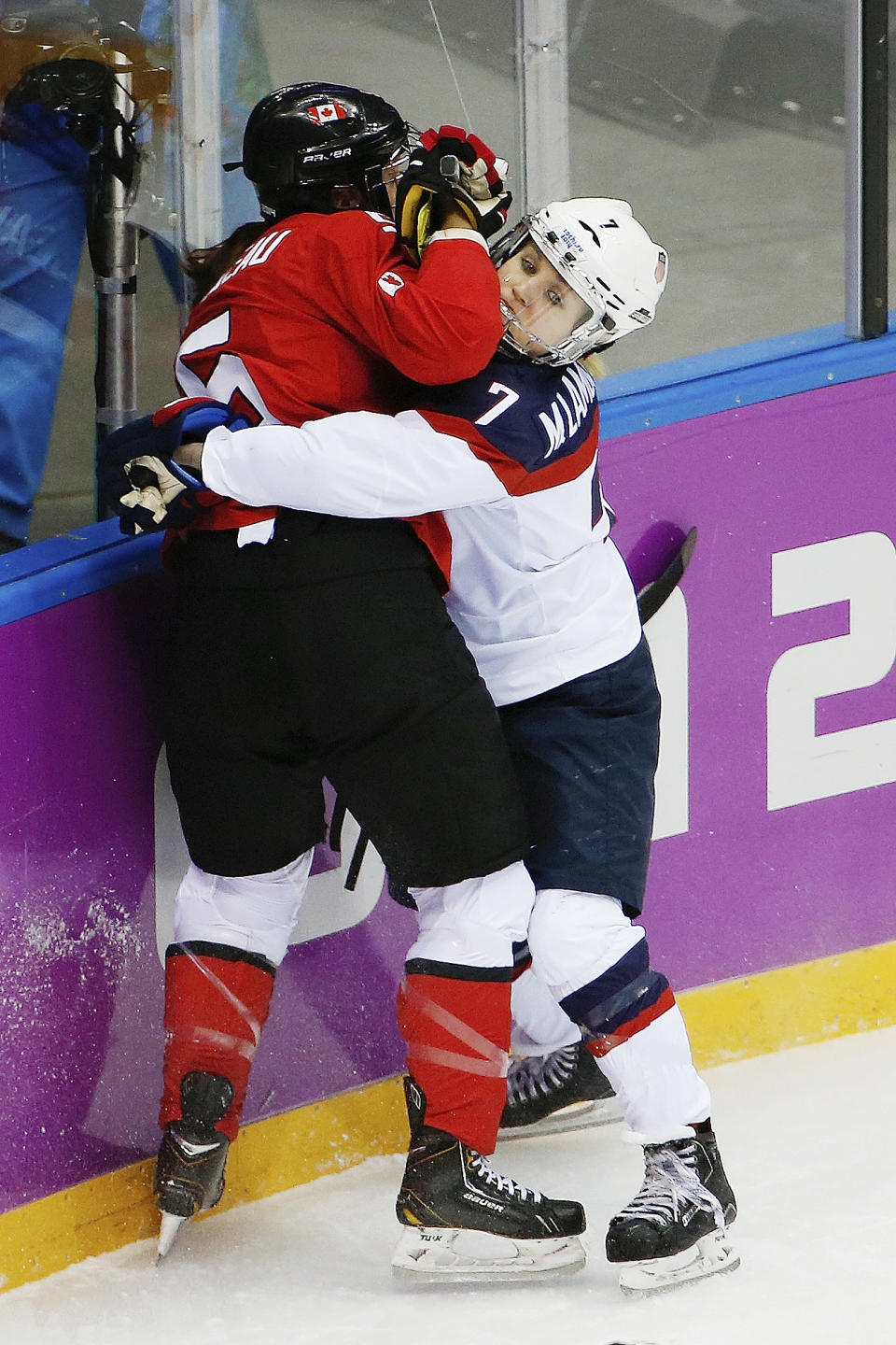 Monique Lamoureux of the United States (7) pins Lauriane Rougeau of Canada (5) against the boards during the first period of the women's gold medal ice hockey game at the 2014 Winter Olympics, Thursday, Feb. 20, 2014, in Sochi, Russia. (AP Photo/Julio Cortez)