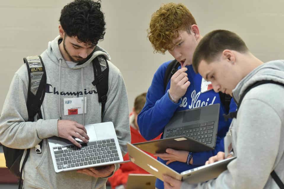 Falmouth High School seniors Marcus Cardoza, left, Nicholas Carnevali and Asa Miller, right, run the numbers on Friday after visiting one of the booths at a financial planning workshop called Credit For Life.