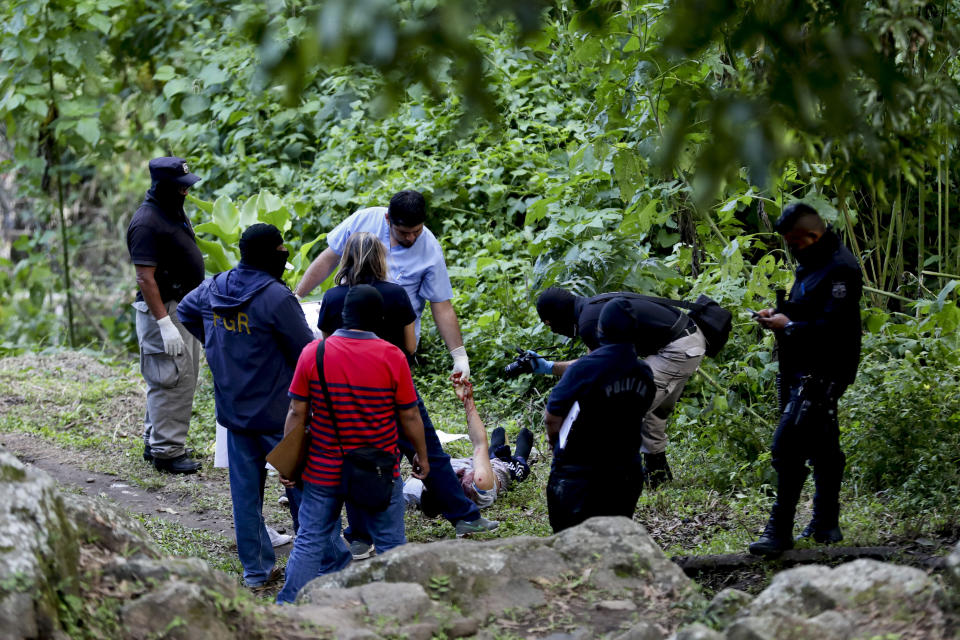 In this Oct. 13, 2019, photo, forensic workers examine the scene where David Rivera, an ex-gang member, lies in San Salvador, El Salvador. Like much of Central America’s massive migration of recent years, the driving force has been fear. (AP Photo/Eduardo Verdugo)