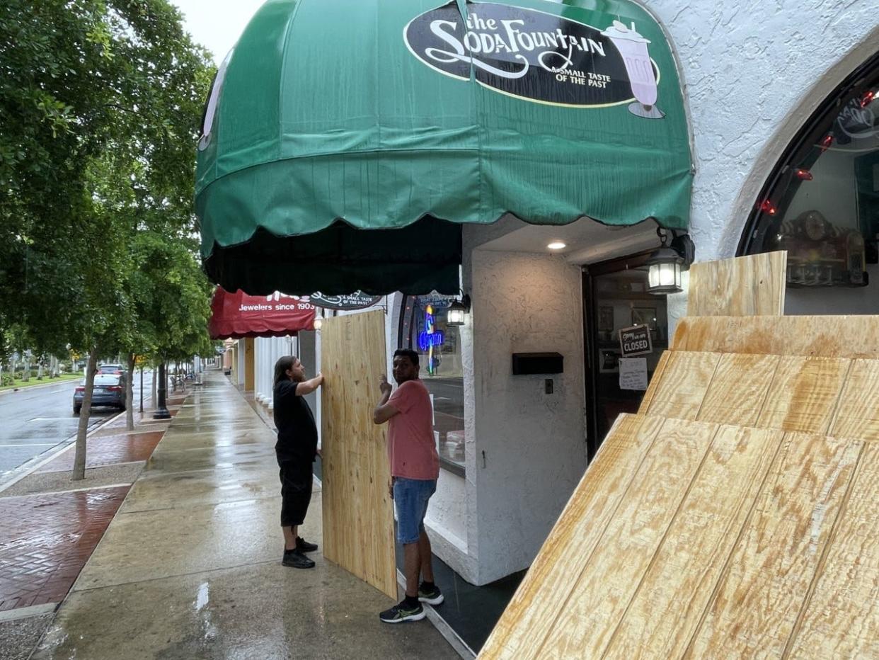 Chris Iovanna and Nick Patel, owner of the Soda Fountain in Venice, begin to board up the store before Hurricane Ian makes landfall.