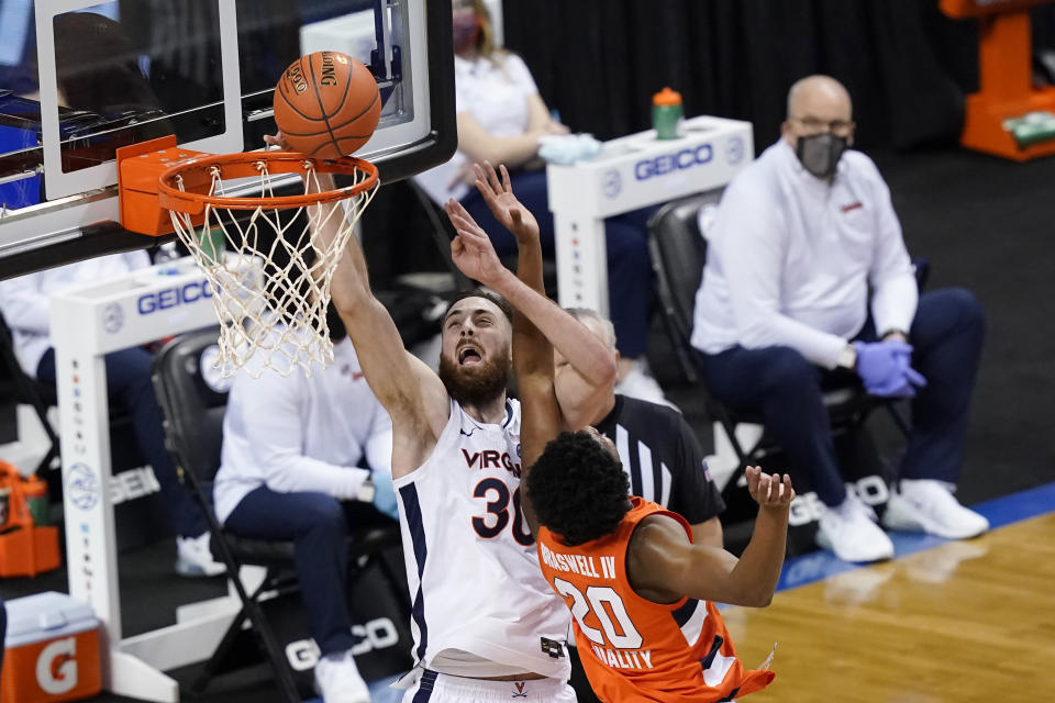 Virginia forward Jay Huff (30) goes up for a basket as Syracuse forward Robert Braswell (20) gets tangled during the first half of an NCAA college basketball game in the quarterfinal round of the Atlantic Coast Conference tournament in Greensboro, N.C., Thursday, March 11, 2021. (AP Photo/Gerry Broome)