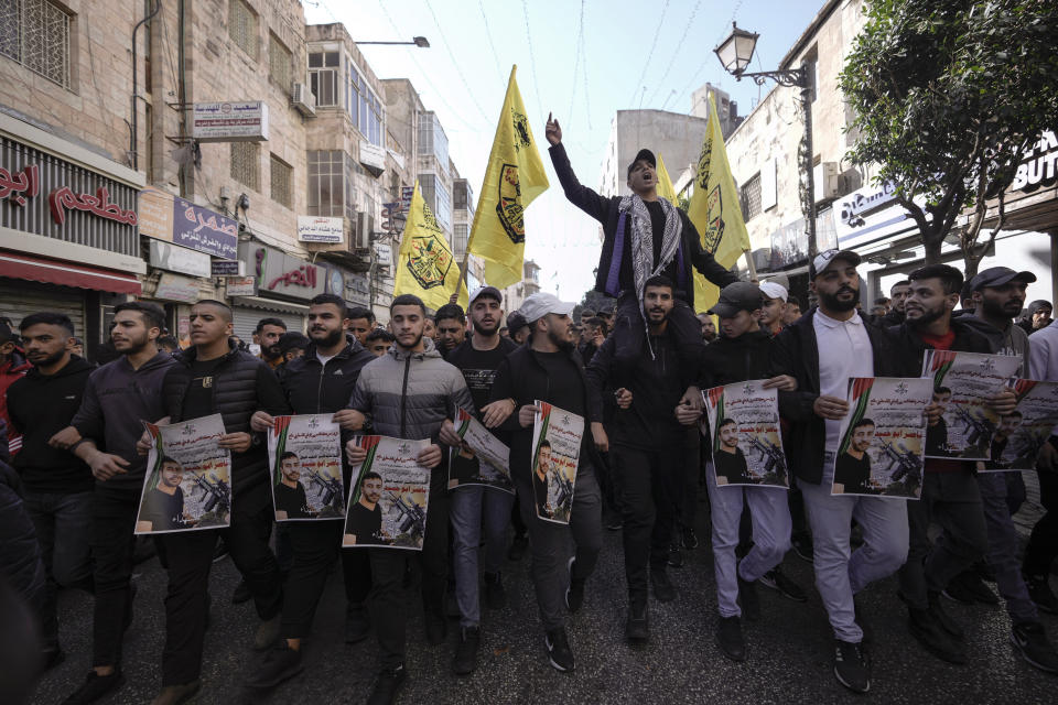 Palestinians hold posters of Palestinian prisoner Nasser Abu Hamid during a protest, Tuesday, Dec. 20, 2022, in the West Bank city of Ramallah, after he died of lung cancer in Israel. Abu Hamid was a former leader of the Al Aqsa Martyrs' Brigade, the armed wing of Palestinian President Mahmoud Abbas's Fatah party. He had been serving seven life sentences after being convicted in 2002 for involvement in the deaths of seven Israelis during the second Palestinian intifada, or uprising, against Israel's occupation in the early 2000s. (AP Photo/Majdi Mohammed)