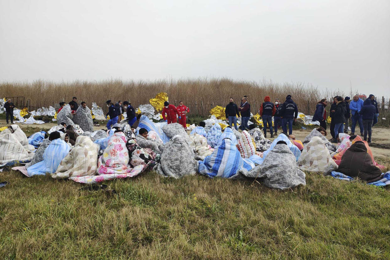 Rescued migrants sit covered in blankets at a beach near Cutro, southern Italy, Sunday, Feb. 26, 2023. Nearly 70 people died in last week's shipwreck on Italy's Calabrian coast. The tragedy highlighted a lesser-known migration route from Turkey to Italy for which smugglers charge around 8,000 euros per person. (Antonino Durso/LaPresse via AP, File)