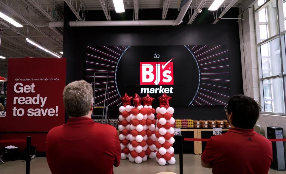 Employees watch as the giant video monitor at the store entrance runs through its display sequence at the new BJ's Market in Warwick .