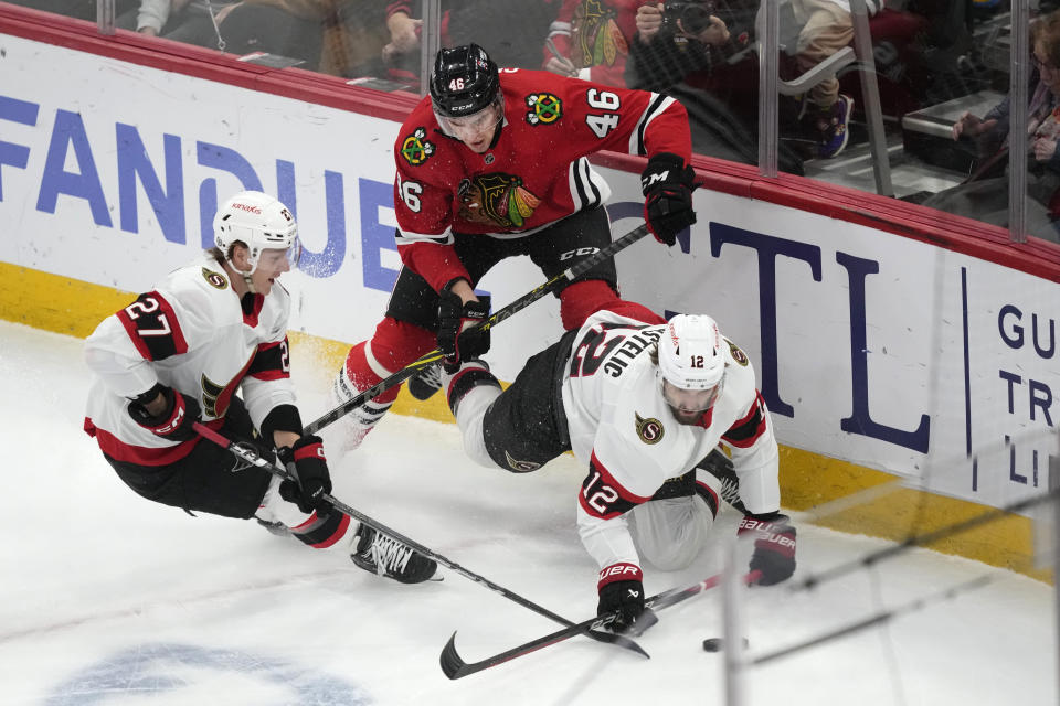 Chicago Blackhawks' Louis Crevier (46) checks Ottawa Senators' Mark Kastelic (12) to the ice as Parker Kelly watches during the first period of an NHL hockey game Saturday, Feb. 17, 2024, in Chicago. (AP Photo/Charles Rex Arbogast)