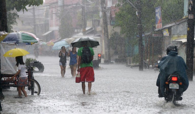 Residents wade through water as heavy rains brought on by Typhoon Utor hit Manila on August 12, 2013. The Philippine's National Disaster Risk Reduction and Management Council said the death toll from the typhoon had risen to six, with five people still missing