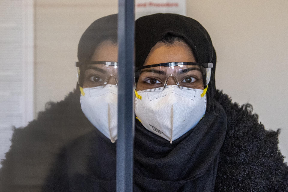 Register nurse, Hubba Manzoor, looks on behind a plexiglass wall as she waits to receive a COVID-19 vaccine at at PowerBack Rehabilitation, in Phoenixville, Pa., Monday, Dec. 28, 2020. (Jose F. Moreno/The Philadelphia Inquirer via AP)