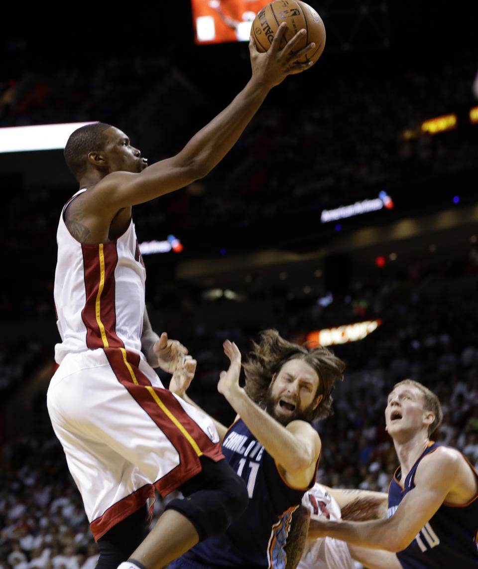 Miami Heat's Chris Bosh, left, shoots over Charlotte Bobcats' Josh McRoberts (11) during the first half in Game 2 of an opening-round NBA basketball playoff series, Wednesday, April 23, 2014, in Miami. (AP Photo/Lynne Sladky)