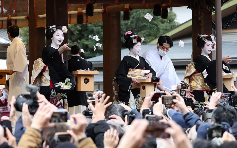 Apprentice geishas, known as maikos, distribute beans to drive away evil spirits to the crowds at a festival in Kyoto to celebrate the coming of spring