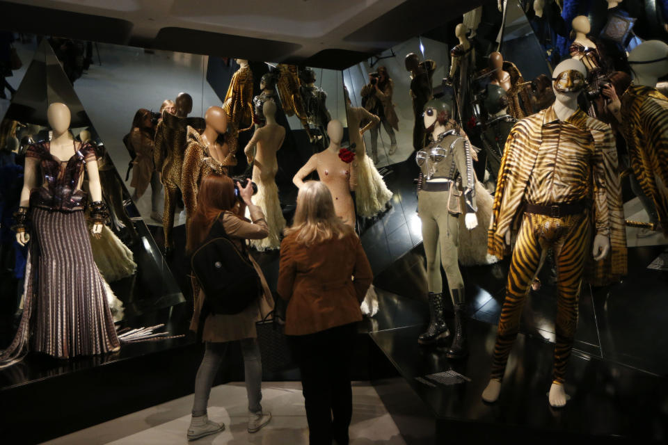 Visitors look at the creations of French couturier Jean Paul Gaultier during the launch of his exhibition 'The Fashion World of Jean Paul Gaultier : From the Sidewalk to the Catwalk' at the Barbican Art Gallery in London, Tuesday, April 8, 2014. (AP Photo/Sang Tan)