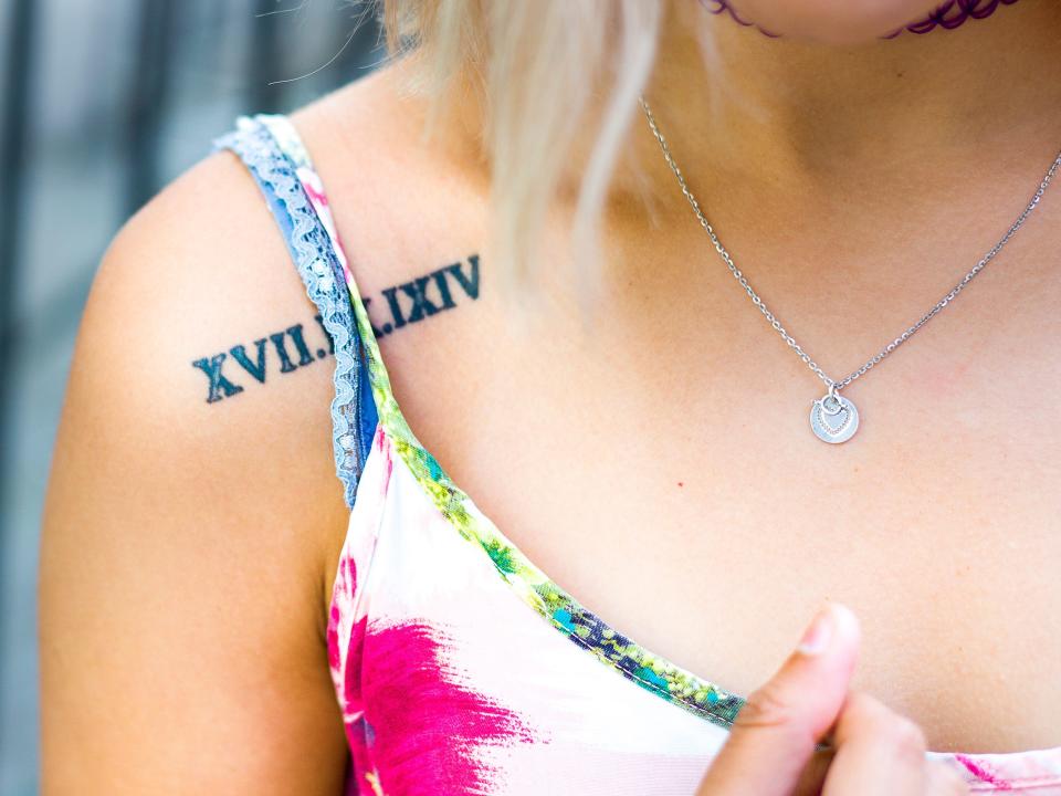 Woman with roman numeral date tattoo on shoulder