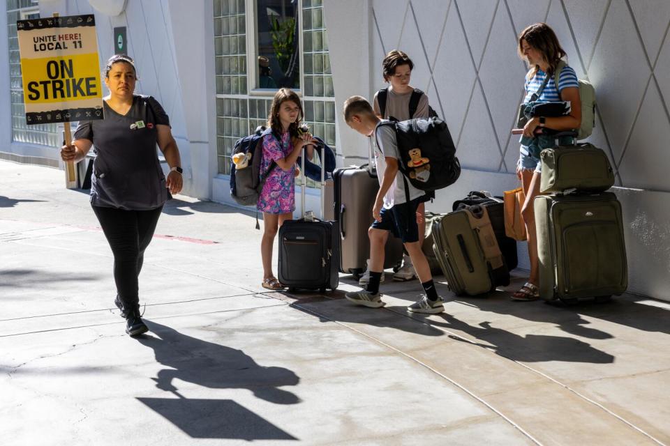 A striking hotel worker walks past hotel guests