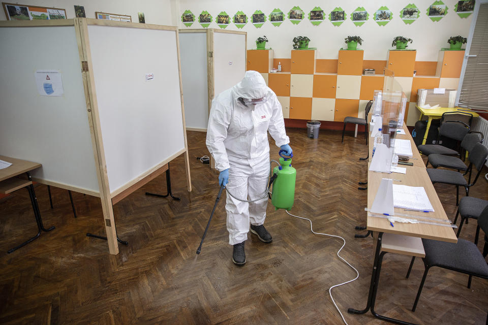 A health worker sprays disinfectant at a polling station during parliamentary elections in the town of during the parliamentary elections in the town of Bankya, Bulgaria, Sunday, April 4, 2021. Bulgarians are heading to the polls on Sunday to cast ballots for a new parliament after months of anti-government protests and amid a surge of coronavirus infections. (AP Photo/Visar Kryeziu)