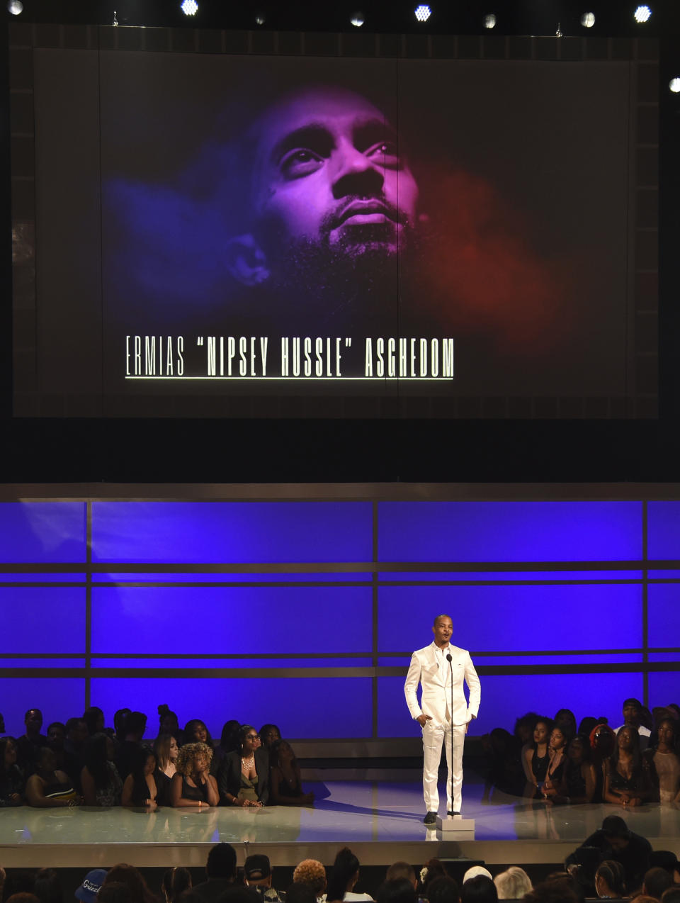 FILE - This June 23, 2019 file photo shows Tip "T.I." Harris presents the humanitarian award to late rapper Nipsey Hussle at the BET Awards in Los Angeles. Hussle, 33, was shot and killed outside his Los Angeles clothing store on March 31, 2019. A year after Hussle's death, his popularity and influence are as strong as ever. He won two posthumous Grammys in January, he remains a favorite of his hip-hop peers and his death has reshaped his hometown of Los Angeles in some unexpected ways. (Photo by Chris Pizzello/Invision/AP, File)