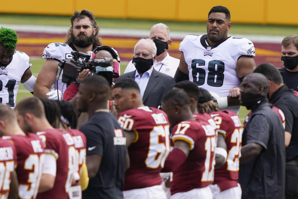 Philadelphia Eagles team owner Jeffrey Lurie, center, joins members of the Philadelphia Eagles and Washington Football Team on the field before the start of an NFL football game, Sunday, Sept. 13, 2020, in Landover, Md. (AP Photo/Alex Brandon)