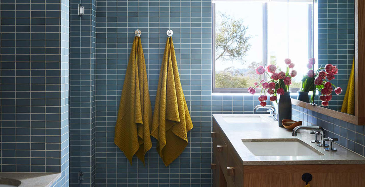  Towels hanging up in a blue tiled bathroom. 