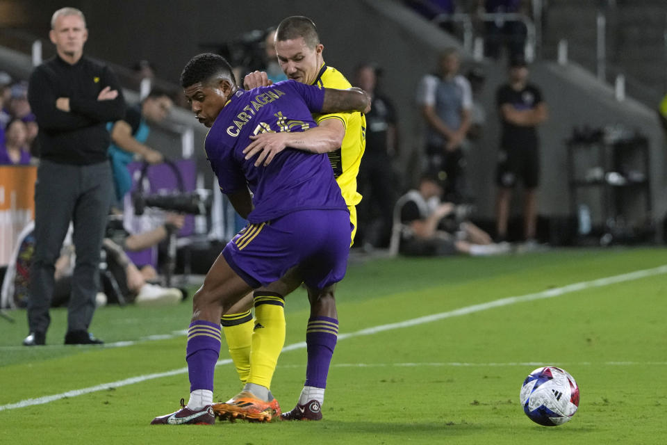 Orlando City midfielder Wilder Cartagena, left, and Nashville SC midfielder Alex Muyl get tangled up trying to get to the ball during the first half of an MLS playoff soccer match, Monday, Oct. 30, 2023, in Orlando, Fla. (AP Photo/John Raoux)