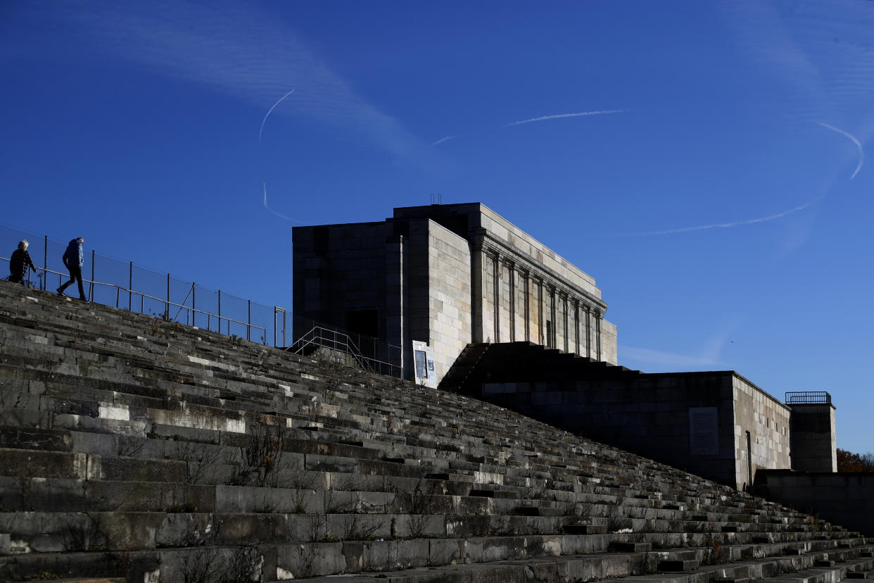 People climb up stairs at the 'Zeppelinfeld' besides the main tribune of the 'Reichsparteigelande' (Nazi Party Rally Grounds) in Nuremberg, Germany, Wednesday, Nov. 18, 2020. Germany marks the 75th anniversary of the landmark Nuremberg trials of several Nazi leaders and in what is now seen as the birthplace of a new era of international law on Friday, Nov. 20, 2020. (AP Photo/Matthias Schrader)