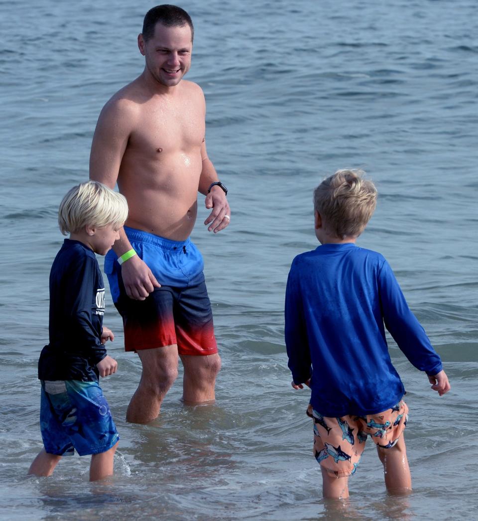 A man trying to coax his young sons into the ocean at Monday's Hair of the Dog Walk/Run/Plunge event at Bethany Beach in January of 2024.
