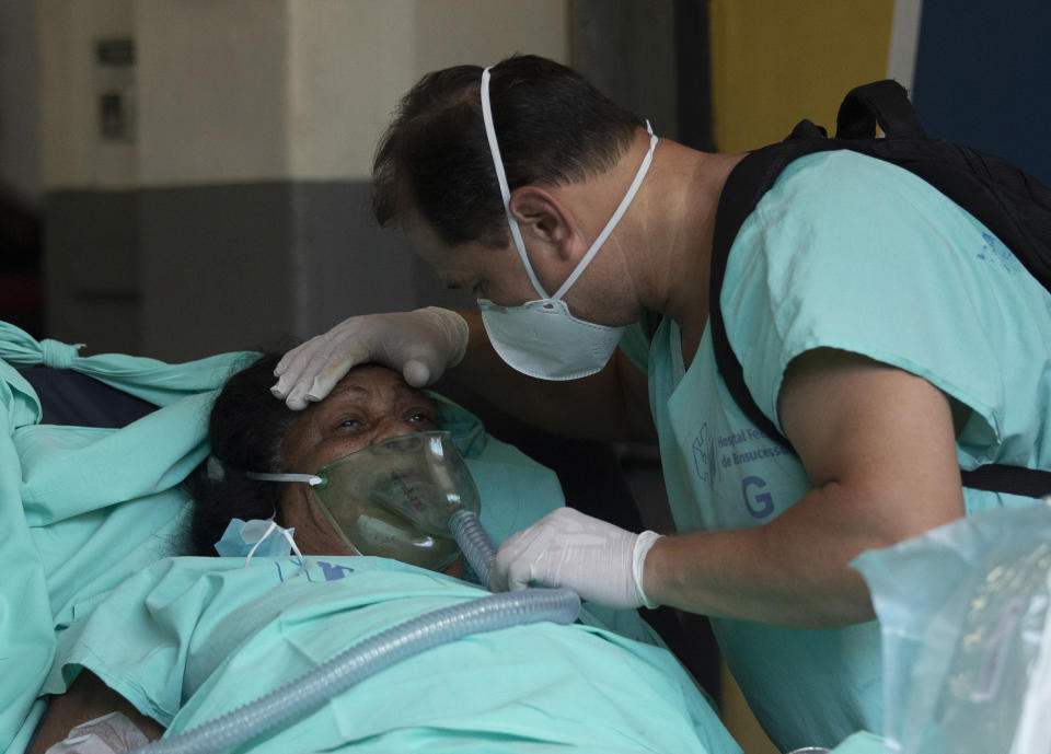 A patient is successfully evacuated from the Bonsucesso Federal Hospital while firefighters douse a blaze in Rio de Janeiro, Brazil, Tuesday, Oct. 27, 2020. According to the hospital, a 42-year-old female COVID-19 patient, who was in critical condition, died while she was being evacuated. (AP Photo/Silvia Izquierdo)