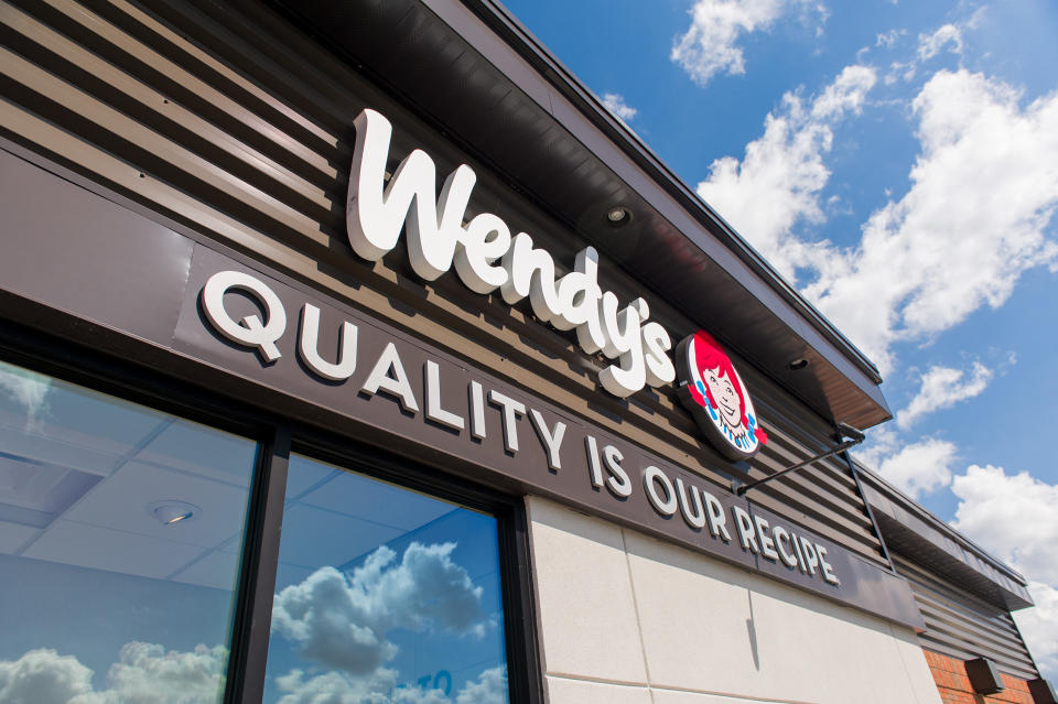 An exterior shot of a renovated Wendy's restaurant with a background of clouds and blue sky.