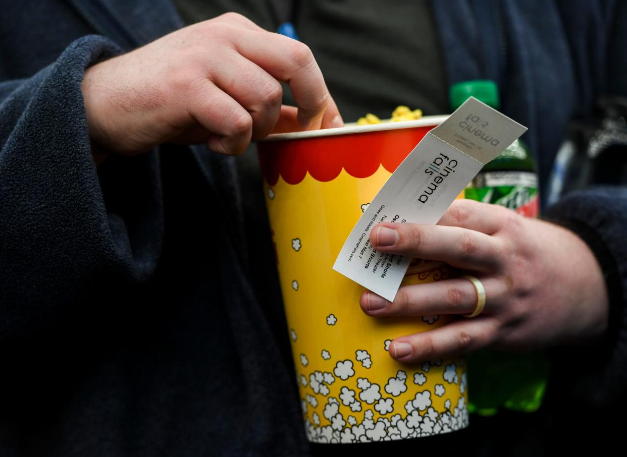 A moviegoer holds their ticket and popcorn while waiting in line in this Argus Leader file photo.