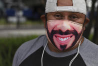 Fabian Santos, a street vendor and supporter of El Salvador's President Nayib Bukele poses with a Bukele mask outside a vaccination center in San Salvador, El Salvador, Tuesday, June 22, 2021. El Salvador has already covered a little more than a million people vaccinated with the first dose of the vaccine and this week announced that people over the age of 35 can now be vaccinated. (AP Photo/Salvador Melendez)