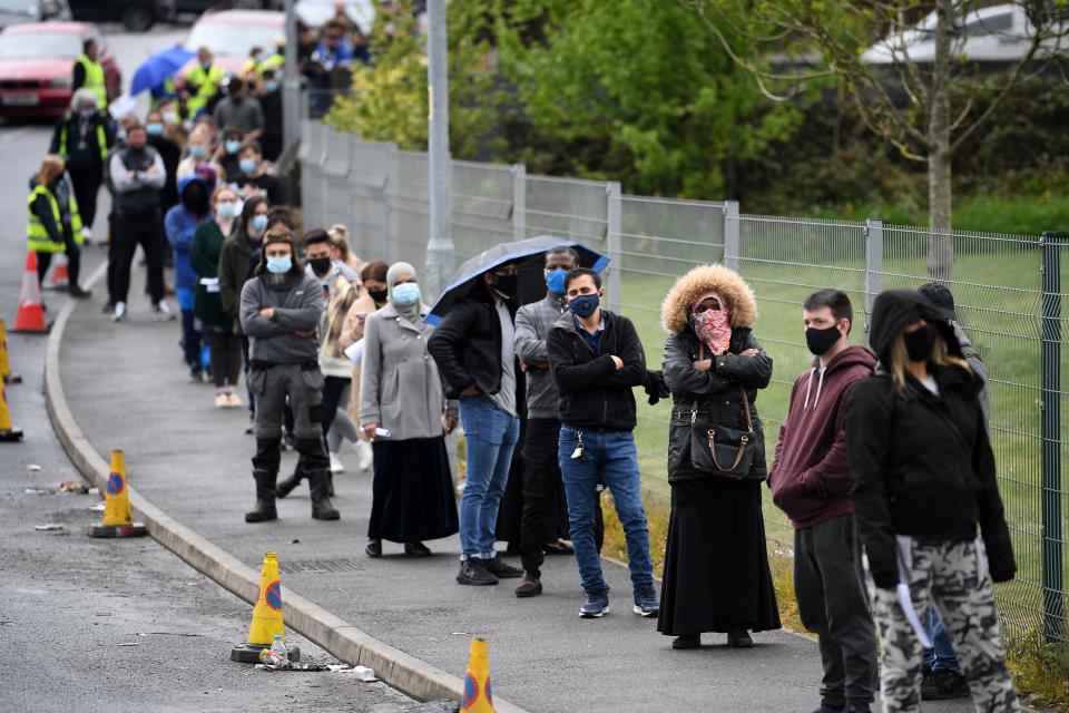 Members of the public queue to receive a Covid-19 vaccine at a temporary vaccination centre at the Essa academy in Bolton, northwest England on May 17, 2021. (Photo by Oli SCARFF / AFP) (Photo by OLI SCARFF/AFP via Getty Images)