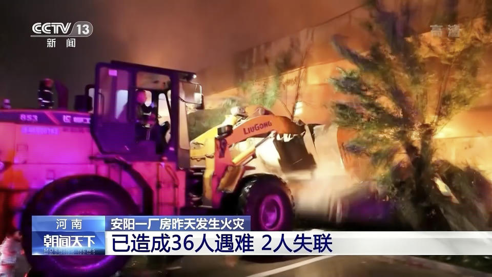 In this image taken from video footage run by China's CCTV, rescuers use a bulldozer to knock over a wall at a fire at an industrial wholesaler in Anyang in central China's Henan province, Monday, Nov. 21, 2022. A fire has killed several dozen people at a company dealing in chemicals and other industrial goods in central China's Henan province. (CCTV via AP)