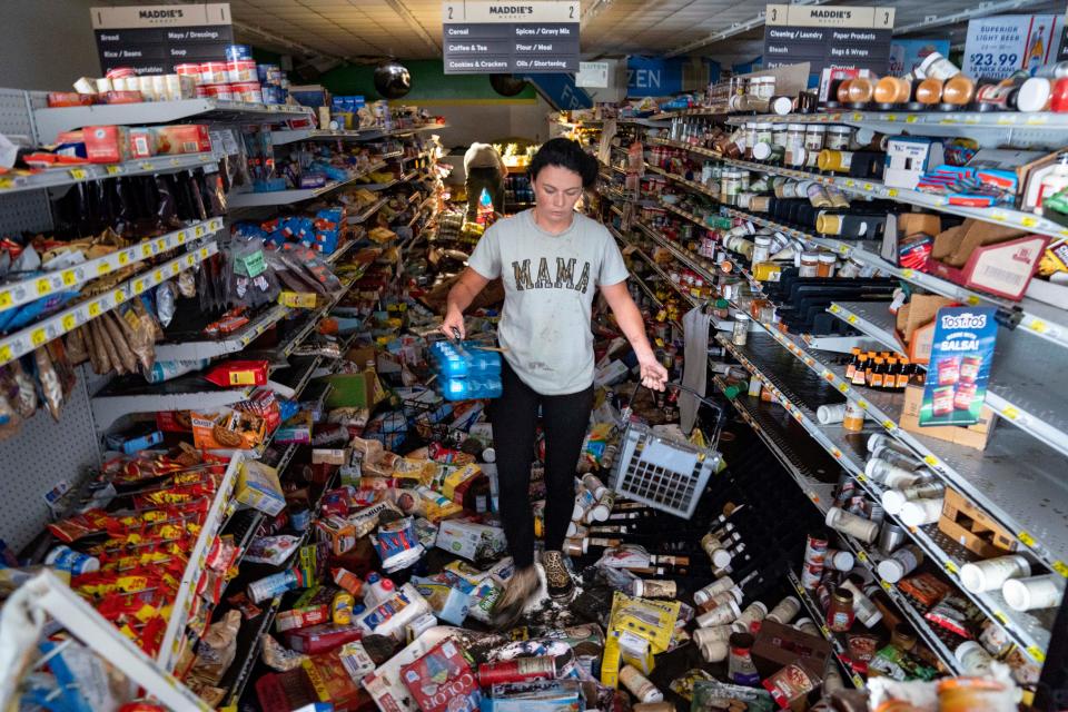 Cassandra Randall grabs food Friday after Maddie's Market in Steinhatchee was flooded and the manager told people to take what they wanted for free after Hurricane Helene flooded the place. Randall's mother-in-law manages the store.