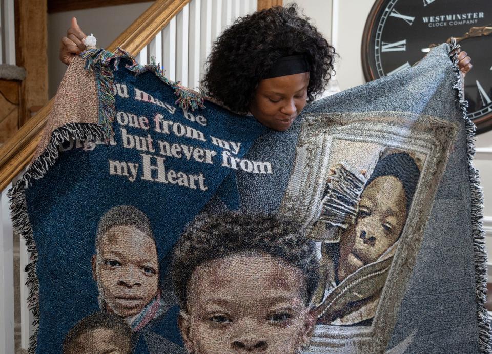 Chrystyna McGibboney looks at a blanket covered in images of her son, Devin Gilbert III, Wednesday, Dec. 13, 2023, at the Bishop Law Firm in Indianapolis. The 15-year-old had a reputation for helping family members with yard work and other chores.