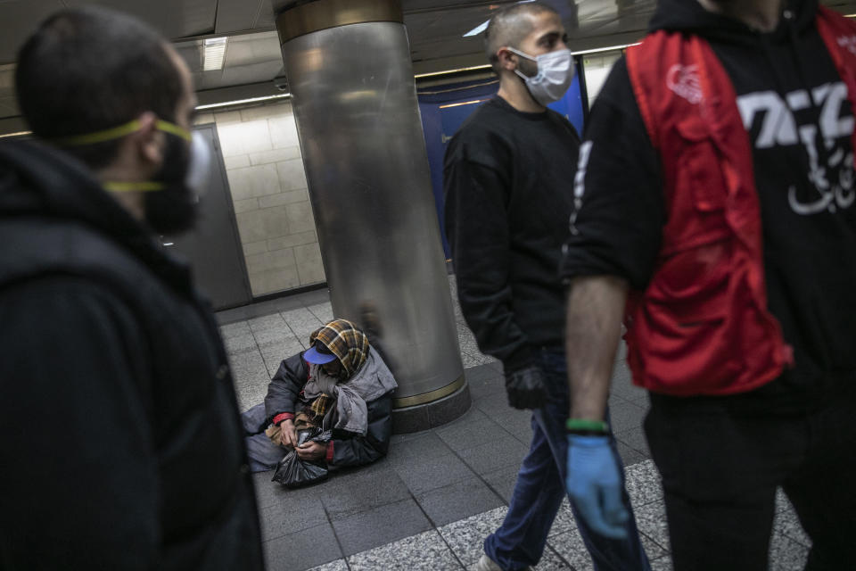 A homeless man in New York's Penn station opens a packet of food given to him by Hamza Deib, owner of Taheni Mediterranean Grill, center, and Mohammed Widdi, Coordinator at Muslims Giving Back, on Friday, May 1, 2020. (AP Photo/Wong Maye-E)