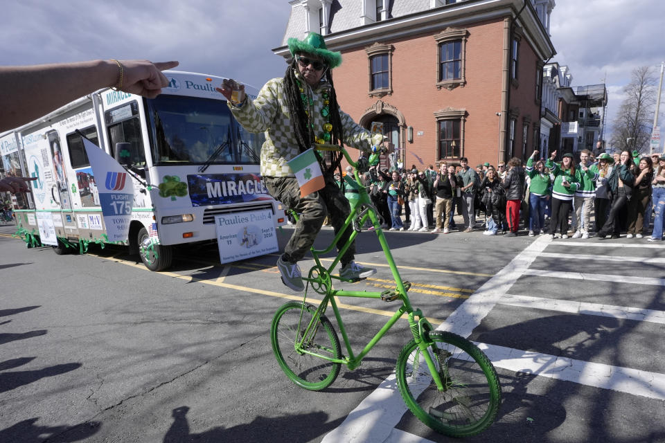 A man on a bicycle greets spectators during the St. Patrick's Day parade, Sunday, March 17, 2024, in Boston's South Boston neighborhood. (AP Photo/Steven Senne)