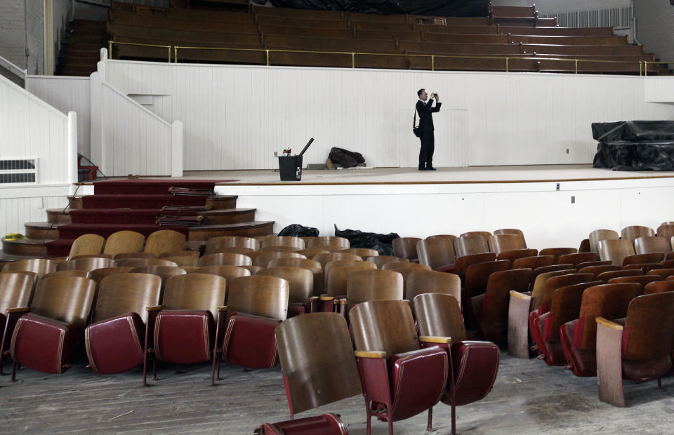 Christopher Chou, chief of staff at the World Evangelical Alliance, shoots a picture of the auditorium being renovated on an historic 217-acre campus in Northfield, Mass., in this photo taken Thursday, March 8, 2012. The campus, along with its 43 buildings, is being offered for free to an orthodox Christian group who can come up a solid plan to use it. (AP Photo/Elise Amendola)