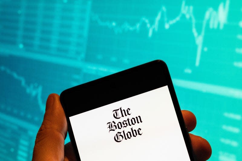 CHINA - 2023/02/15: In this photo illustration, the American daily newspaper The Boston Globe logo seen displayed on a smartphone with an economic stock exchange index graph in the background.