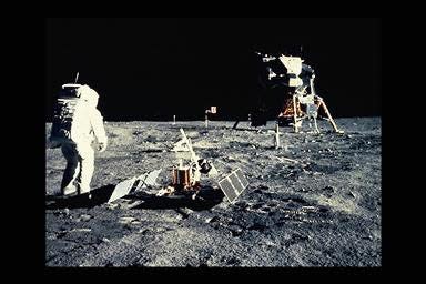 Apollo 11 astronaut Neil Armstrong on the moon with monitoring equipment and lunar lander Eagle in background.