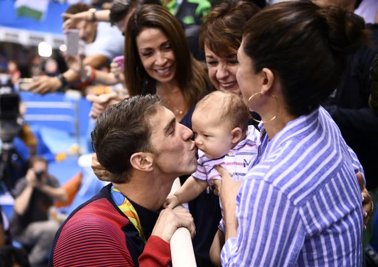 USA's Michael Phelps (L) kisses his son Boomer next to his partner Nicole Johnson (R) and mother Deborah (C) after he won the men's 200m butterfly final on August 9, 2016