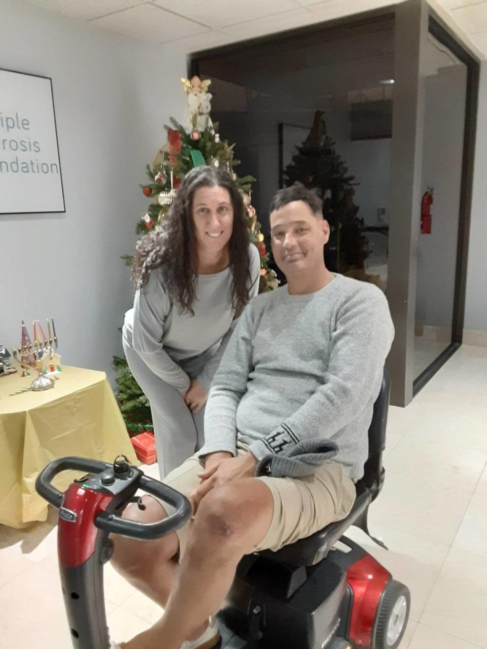 Roy Burger and his wife Erin at the Multiple Sclerosis Foundation in December 2023. Burger has multiple sclerosis and the scooter he needs to get around, plus years of family wear and tear, makes their dining set at home a poor fit. Burger hopes to get a new set via Wish Book but is already grateful with the $600 Miami Herald Charities sent his way so far.