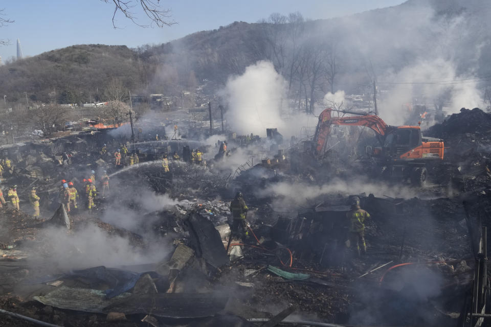 Firefighters and rescue workers clean up the site of a fire at Guryong village in Seoul, South Korea, Friday, Jan. 20, 2023. A fire spread through a neighborhood of densely packed, makeshift homes in South Korea's capital Friday morning. (AP Photo/Ahn Young-joon)