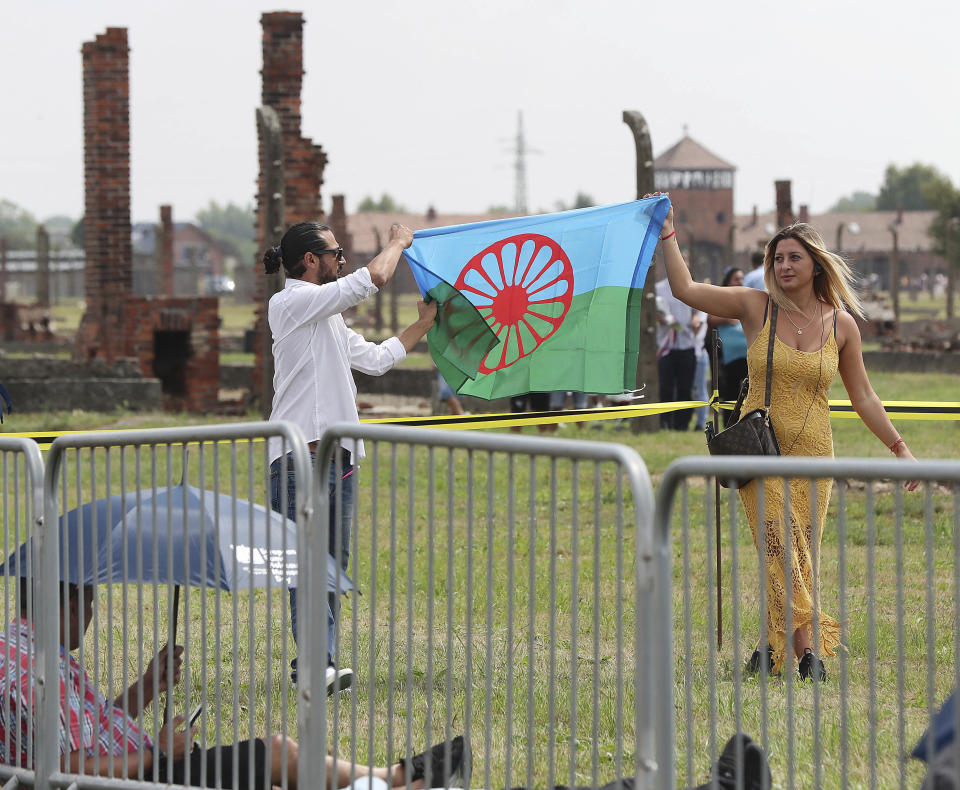 People display a Romani flag to commemorate the Roma and Sinti people killed by Nazi Germany in World War II, during ceremonies at Oswiecim, Poland, Friday Aug. 2, 2019. The American civil rights activist Rev. Jesse Jackson gathered Friday with survivors at the former Nazi death camp of Auschwitz-Birkenau to commemorate an often forgotten genocide — that of the Roma people. (AP Photo/Czarek Sokolowski)