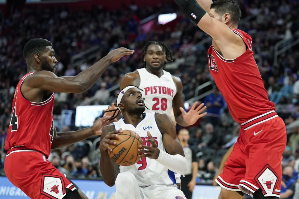 Detroit Pistons forward Jerami Grant (9) is defended by Chicago Bulls forward Patrick Williams, left, and Chicago Bulls center Nikola Vucevic during the first half of an NBA basketball game, Wednesday, Oct. 20, 2021, in Detroit. (AP Photo/Carlos Osorio)