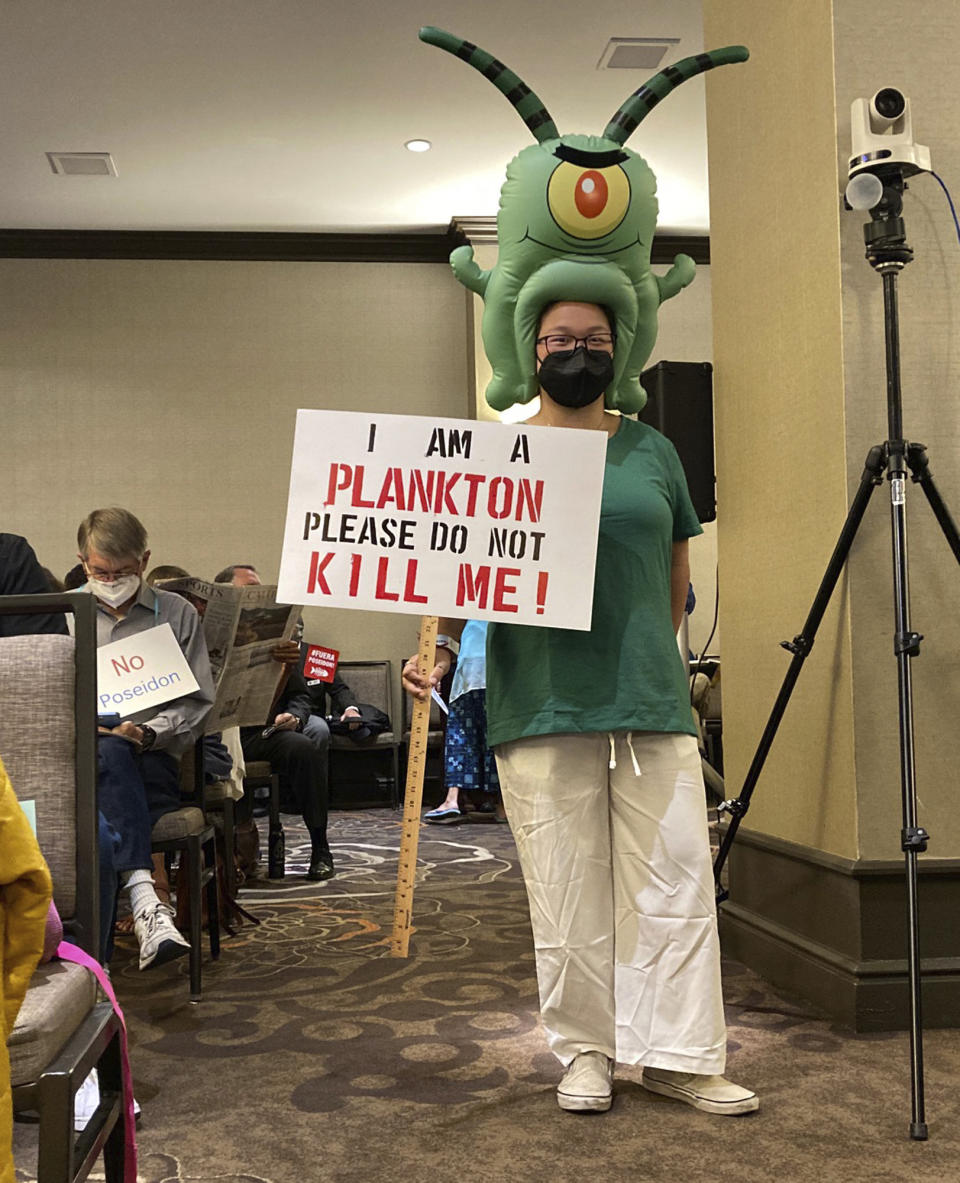 Community members opposed to a proposal to build a $1.4 billion desalination plant in Huntington Beach holds signs at a California Coastal Commission hearing in Costa Mesa, Calif., Thursday May 12, 2022.For more than two decades, California's Orange County has debated whether to build a seaside plant to convert the Pacific Ocean's salt water into drinking water in hopes of buffering against droughts like the one now gripping the nation's most populous state. (AP Photo/Amy Taxin)