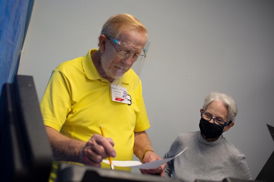 Voting machine operator Bob Henslee prepares a machine for Ellen Williams on the first day of early voting at the Maury County Election Commission in Columbia, Tenn., on Wednesday, Oct. 14, 2020. 